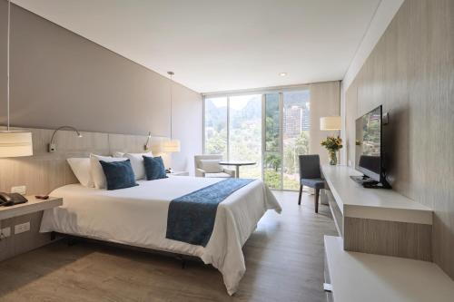 a bedroom with a bed and a desk and a television at Hotel bh Bicentenario in Bogotá