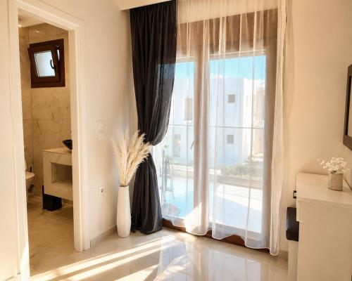 a living room with a large window with curtains at Chrisella Crystal in Skala Rachoniou
