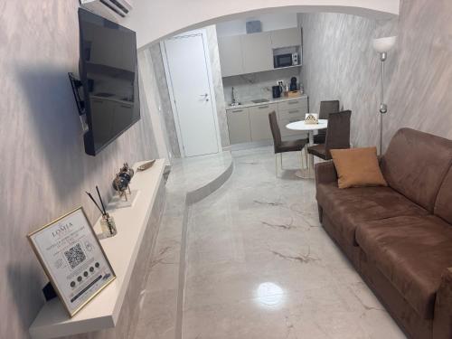 a living room with a brown couch and a kitchen at Romantic Suite Genova in Genoa