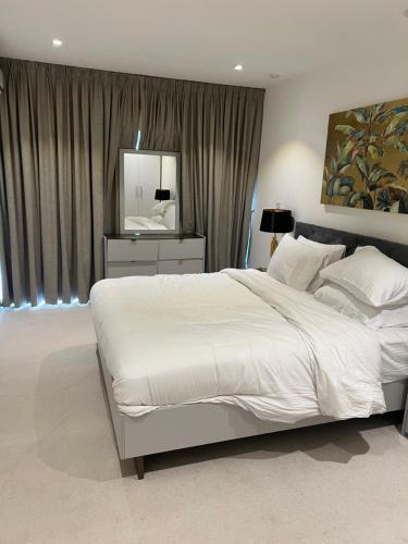 a bedroom with a large white bed and a mirror at Embassy Gardens Studio Accra in Accra