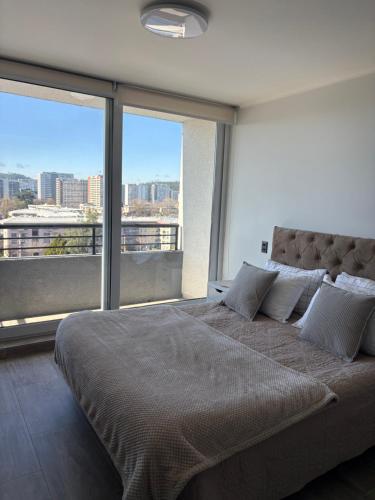 a bedroom with a large bed with a large window at Studio cómodo y luminoso, a pasos del centro! - Bilingual Support Eng, Esp in Concepción