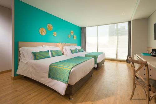 two beds in a bedroom with a green wall at bh Barranquilla in Barranquilla