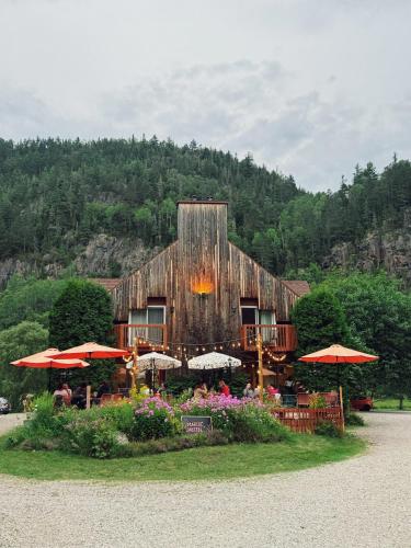 a large wooden building with umbrellas in front of it at Auberge du Jardin in Petit-Saguenay