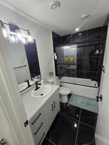 a bathroom with a sink and a toilet and a mirror at The Vilaskan in Saskatoon
