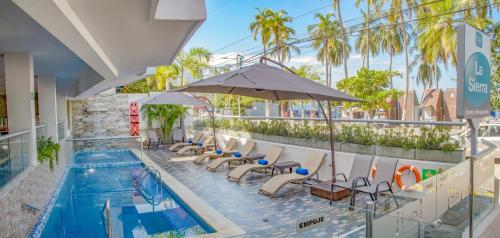 una piscina con lettini e un ombrellone di Hotel Be La Sierra a Santa Marta