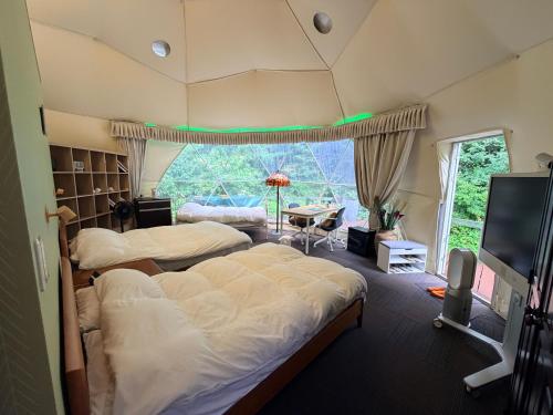 a bedroom with two beds and a tv and a table at 摩天轮下的森 in Tsumagoi