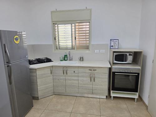 a kitchen with a stainless steel refrigerator and a microwave at פנינת הצפון in Qiryat Shemona