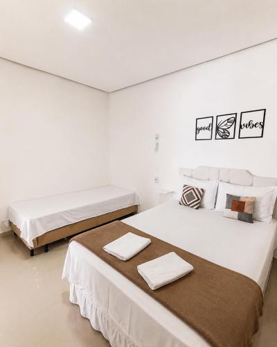 two beds in a white room with towels on them at Pousada Jeitim Mineiro in Capitólio