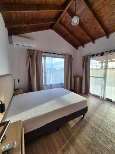 a bedroom with a large bed and large windows at Quintasdeconde in San Miguel del Monte