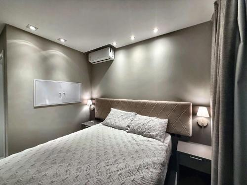 a small bedroom with a bed and two lamps at Studio with pool, pool table, gym and sauna in Itapema