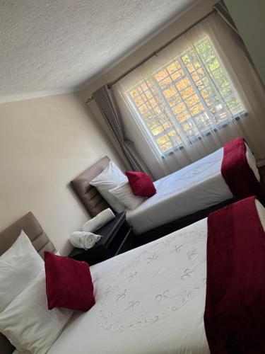 two beds in a hotel room with a window at The Place in Umtali