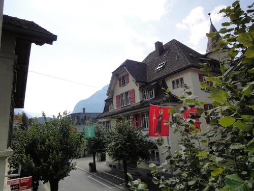 a white building with a black roof and red flags at Ferienwohnung Meiringen in Meiringen