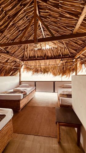 a room with three beds in a straw roof at El Rincón de Juan in San Onofre