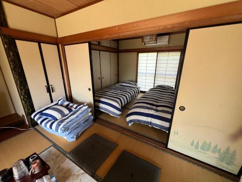 a room with three beds in a room with mirrors at Hillshouse2はなれ in Tokoname