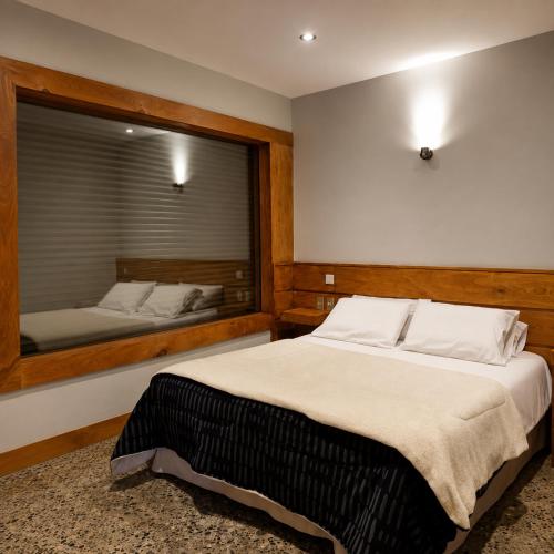 a bedroom with a large bed and a large mirror at Refugio Cordillera Flora endógena Bosque Esclerófilo in San José de Maipo