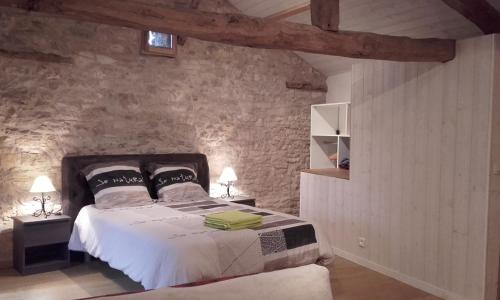 ein Schlafzimmer mit einem Bett und einer Steinmauer in der Unterkunft Studio Du Cluzel in Pontcirq