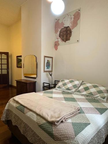 a bedroom with a bed with a checked blanket and a mirror at Hospedaria do Guata in Tibagi
