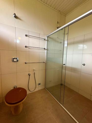 a shower with a toilet and a glass shower stall at Hospedaria do Guata in Tibagi