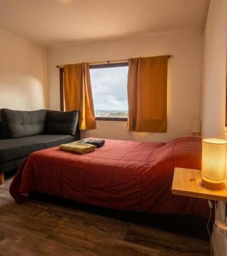 a bedroom with a bed and a couch and a window at Cabaña del Mirador 5 in Puerto Pirámides