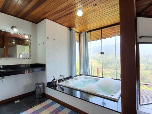 a large bathroom with a tub with a large window at Pousada Bela Mauá in Itatiaia