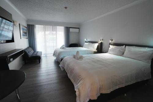 a hotel room with two beds and a chair at Hope Harbour Hotel Apartments in Gold Coast