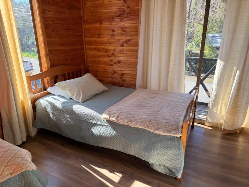 a bedroom with a bed in a room with a window at Refugio Barbara - Coñaripe in Coñaripe