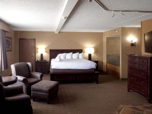 a hotel room with a bed and a chair at Western Heritage Hotel and Conference Center, an Ascend Collection Hotel in Casper
