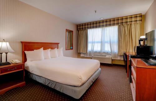 a hotel room with a large bed and a television at Anchorage Inn & Suites - Portsmouth in Portsmouth