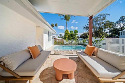 a patio with a couch and a table and a pool at Solara Escape Mooloolaba - Luxe Pet-Friendly Home in Alexandra Headland