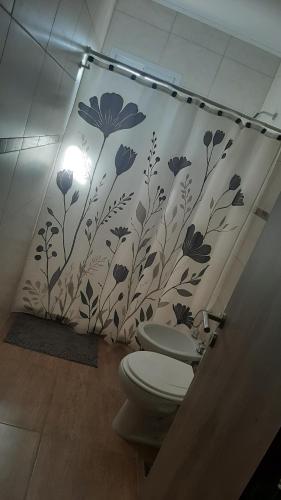 a bathroom with a toilet and a wall with flowers at El Rincon del Descanso in General Alvear