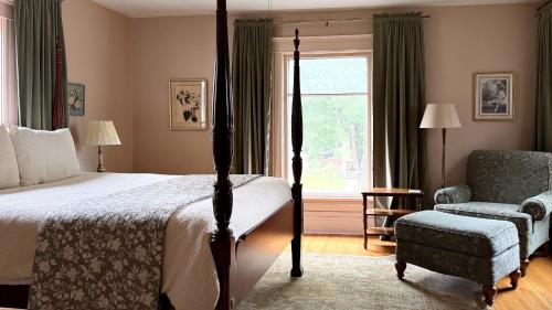 a bedroom with a bed and a chair and a window at Spacious 4 BDR Historic Home in Heart of Sioux Center in Sioux Center