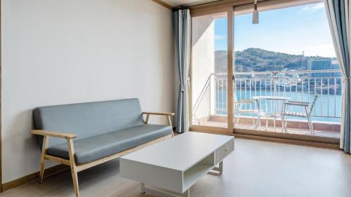 a living room with a couch and a table and a window at Yeosu Turtleship Pension in Yeosu