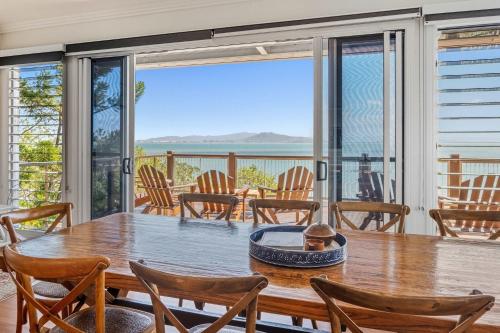 a dining room with a table and chairs and a view of the ocean at Driftwood in Picnic Bay
