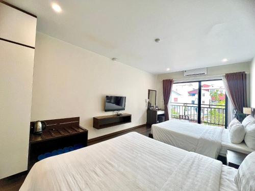 a hotel room with two beds and a television at Paragon Noi bai Hotel & Pool in Thach Loi