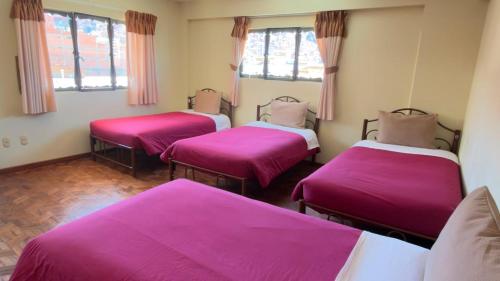 three beds in a room with pink sheets at York House in La Paz