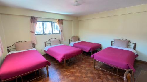 three beds in a room with pink covers at York House in La Paz