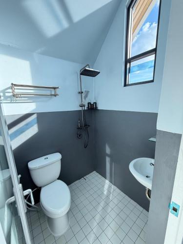 a white bathroom with a toilet and a sink at D'Mount Sky Homestay Syariah in Bukittinggi