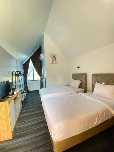 a hotel room with two beds and a television at D'Mount Sky Homestay Syariah in Bukittinggi