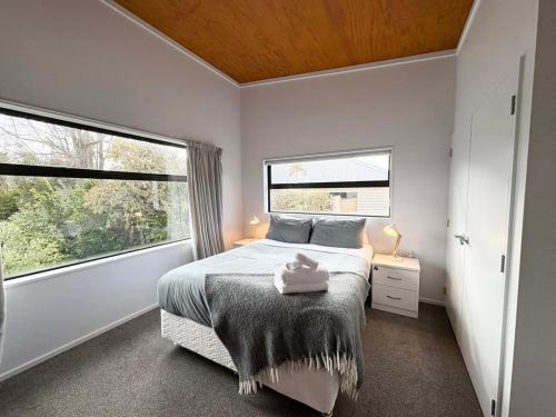 a bedroom with a bed and two windows at The Bach in Lake Tekapo
