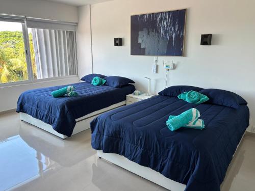 two beds in a bedroom with blue comforter at Brisas Shores Beachfront connecting apartments, Cancun Hotel Zone in Cancún