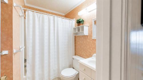 a bathroom with a white shower curtain and a toilet at Oceanfront 1BR • Updated Balcony • Cherry Grove • Sea Cabin 206-A in Myrtle Beach