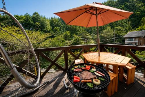 a grill with food and an umbrella on a deck at BLUEBAY TERRACE okutama in Okutama