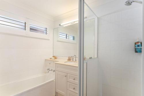 a bathroom with a shower and a sink and a mirror at Blue Summer House in Long Jetty