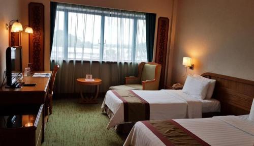 a hotel room with two beds and a window at The CentrePoint Hotel in Kampong Kiulap