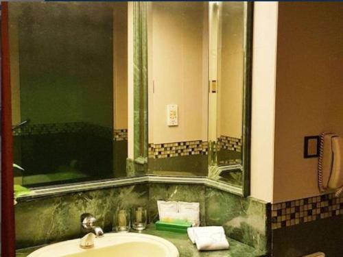 a bathroom with a sink and a large mirror at The CentrePoint Hotel in Kampong Kiulap