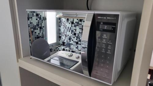 a microwave oven with its door open on a shelf at Luxus Duplex 102m2 Vista Mar - Vilas do Atlântico in Lauro de Freitas