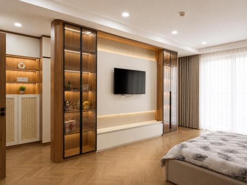 a bedroom with a bed and a tv on a wall at EcoCity Suites BMT in Buôn Enao