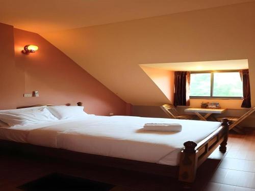 a bedroom with a large white bed and a window at Tai Asean House in Ban Kham Kling
