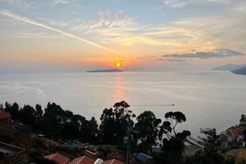 a sunset over a body of water with a city at Sol y Luna in Comunidad Yumani