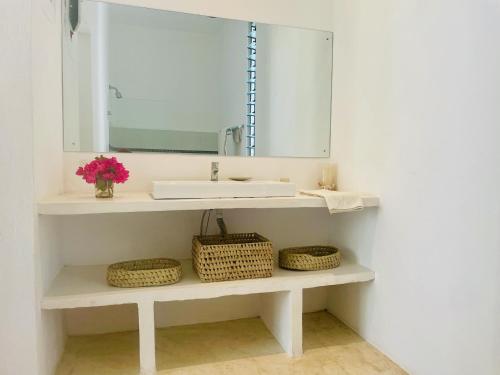a bathroom with a sink and a mirror and baskets at Nyumba Nyekundu in Watamu
